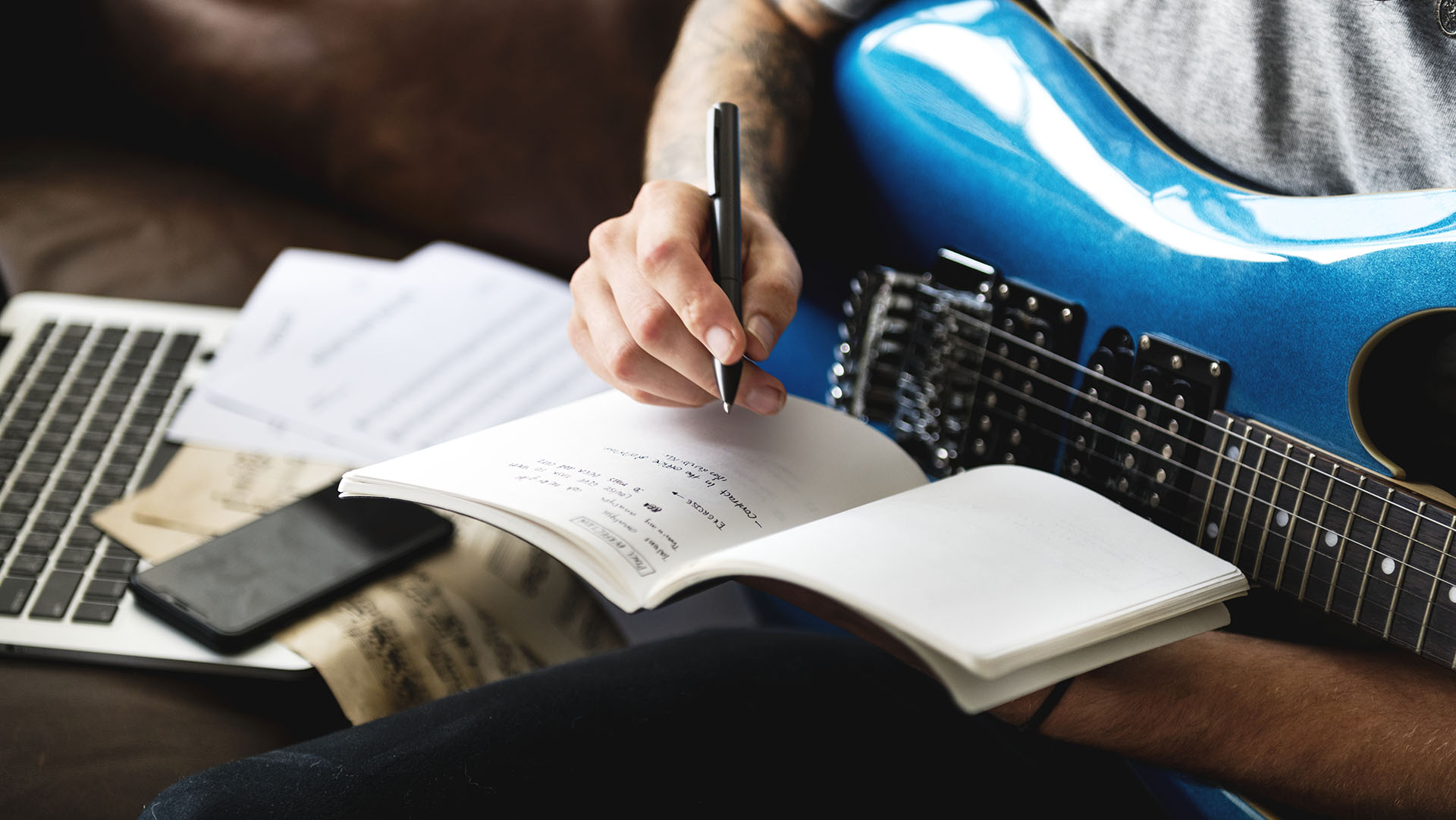 Man writing a song while holding the guitar